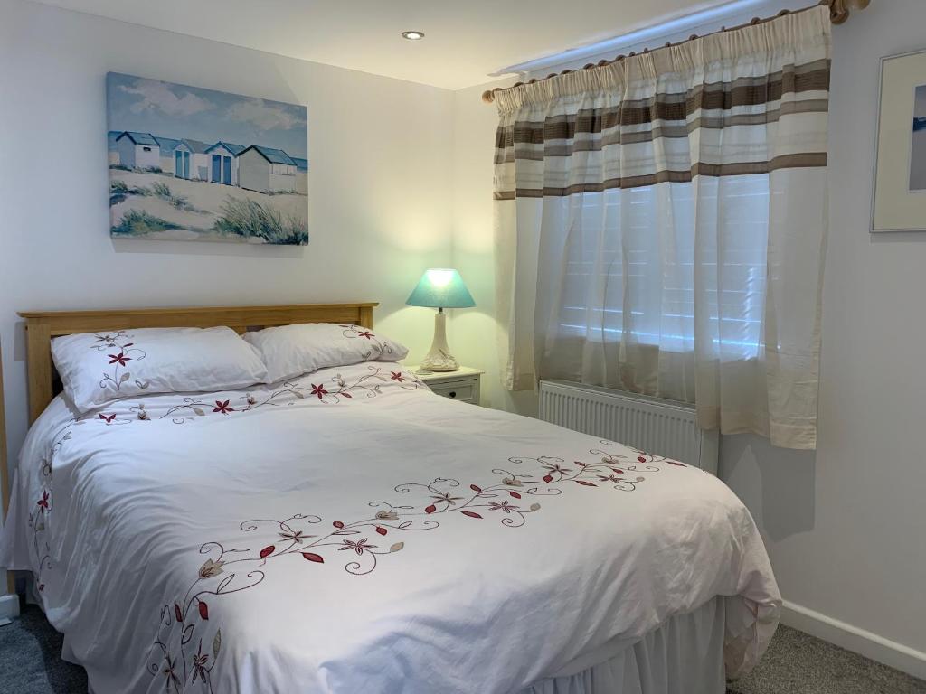 Un dormitorio con una cama blanca con flores. en Self contained annex with bedroom bathroom sitting room and kitchenette, en Emsworth