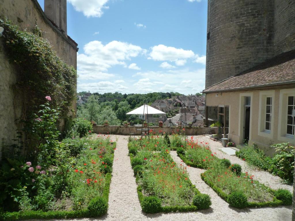 um jardim ao lado de um edifício com um guarda-chuva em La Maison de la Tour em Semur-en-Auxois