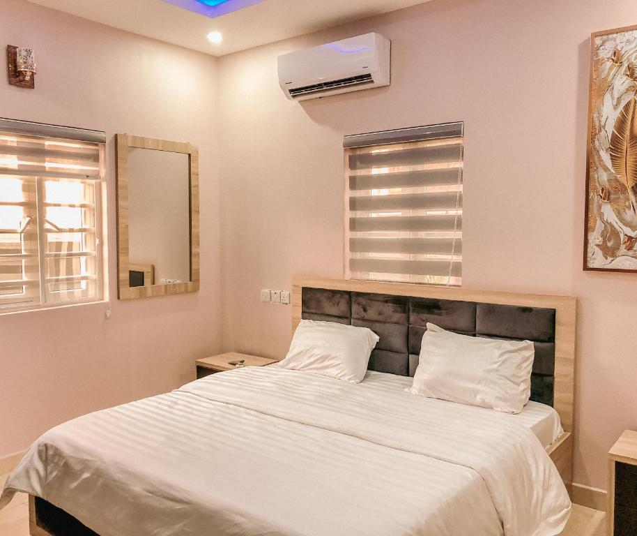 1 dormitorio con 1 cama grande con sábanas blancas en Crayford Homes, en Ikeja
