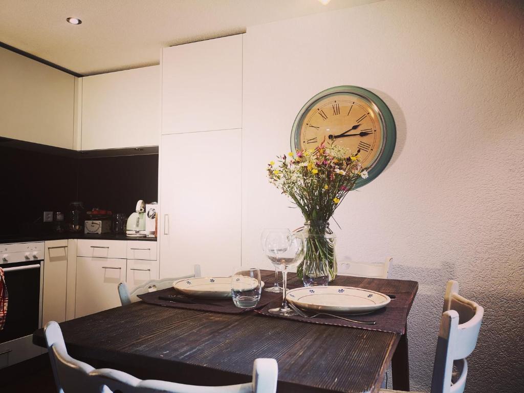 Urchige 2-Zimmerwohnung في Matten: طاولة غرفة طعام مع ساعة على الحائط