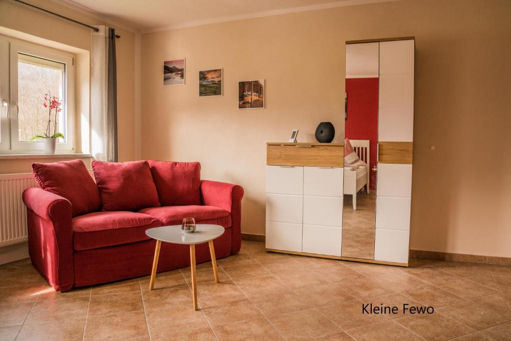 een woonkamer met een rode bank en een spiegel bij Hohlfeld´s Ferienwohnung in Bad Schandau