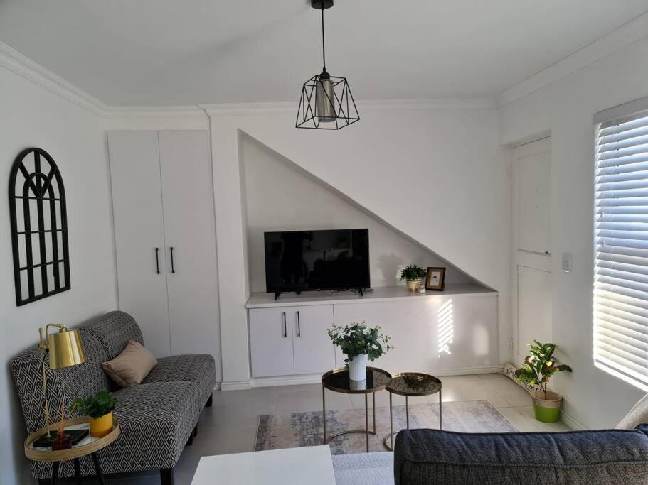 a living room with a couch and a tv at Cozy 2 bedroom APT - Near Kenilworth Racecourse in Cape Town