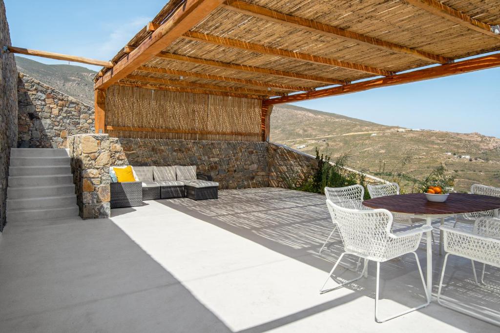 a patio with a table and chairs and a stone wall at Blue Sea Villa in Serifos Chora
