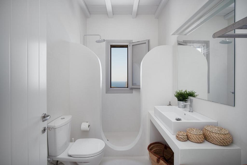 a white bathroom with a toilet and a sink at Blue Sea Villa in Serifos Chora