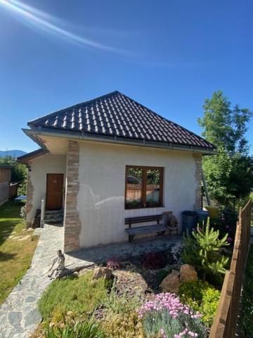 una pequeña casa blanca con un banco en un jardín en Chalupa u dedka Bešeňová -Liptovský Michal, en Liptovský Michal