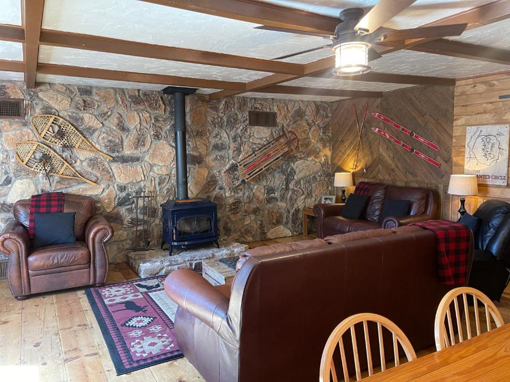 sala de estar con muebles de cuero y pared de piedra. en The Outback On The Creek With High Speed Wifi, en Red River