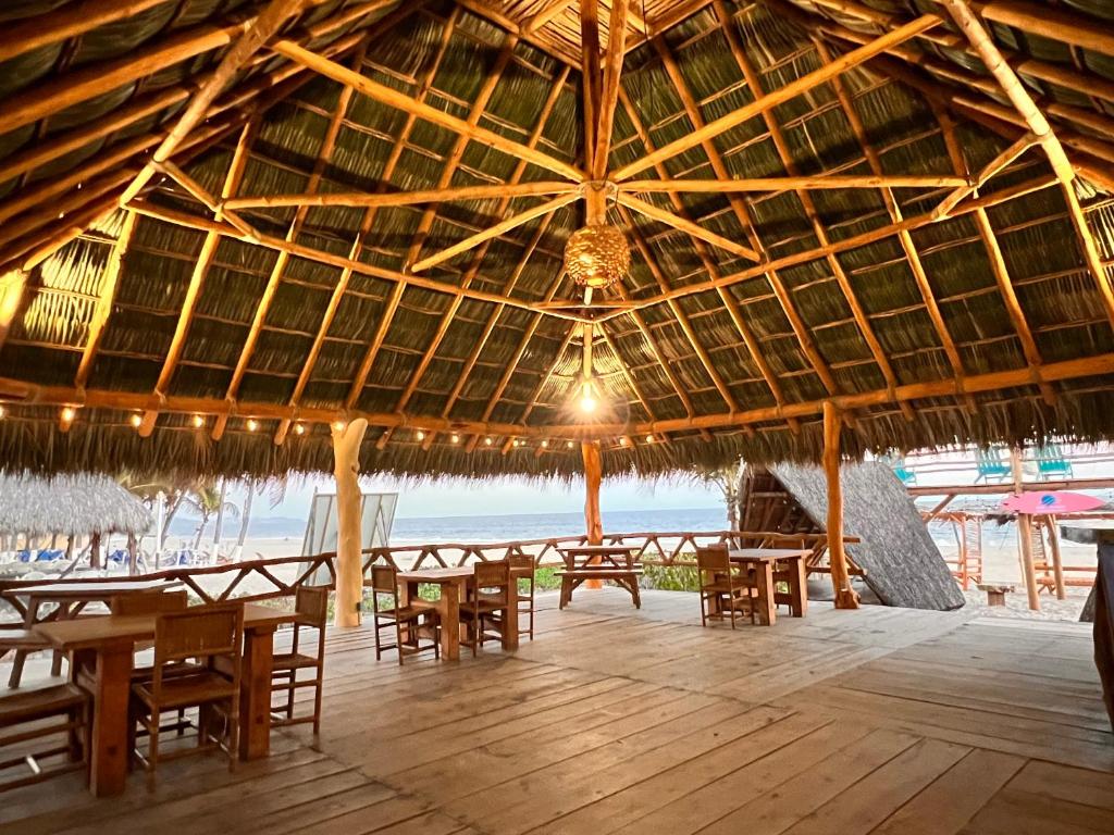 a large straw hut with tables and chairs on the beach at A&V Hotel Boutique in Acapulco