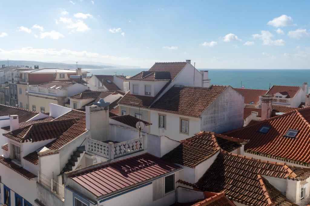 an aerial view of roofs of buildings and the ocean at TikLiving in Ericeira