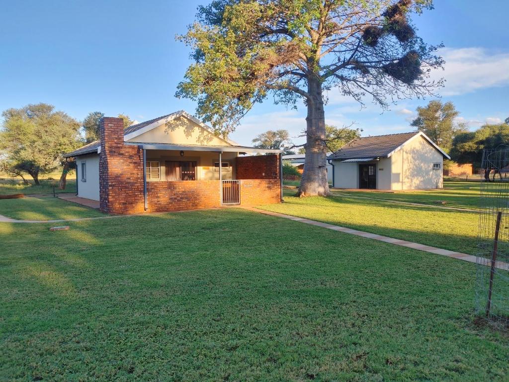 a brick house with a tree in the yard at Mukumbura Swartwater 