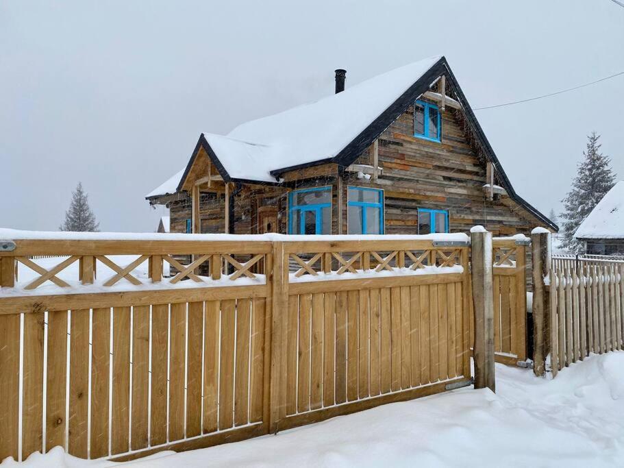 a wooden fence in front of a house with snow at Casuta din Balcesti in Bălceşti