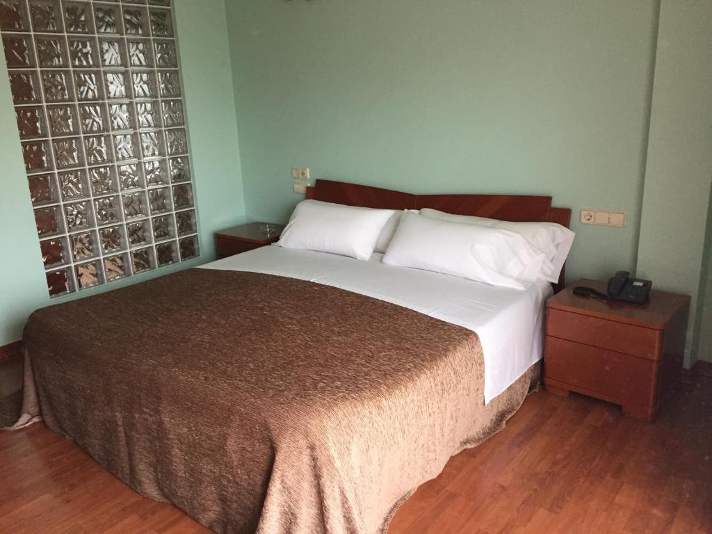 a bedroom with a large bed and a wooden floor at Motel Abalo in Catoira