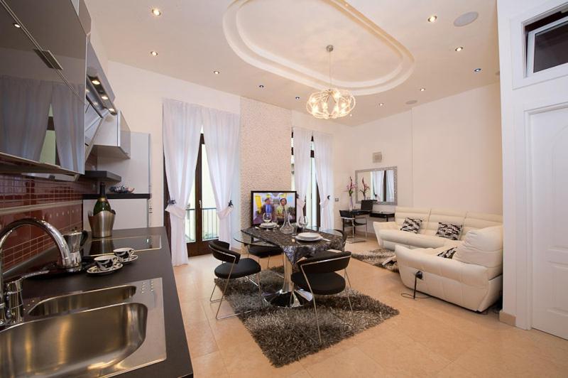 a kitchen and living room with a table and a couch at Appartamenti Luxury Arco in Arco