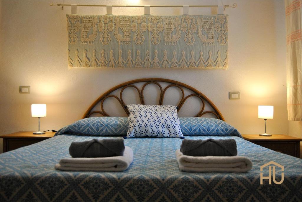sypialnia z niebieskim łóżkiem i ręcznikami w obiekcie Villa Pietra Rossa w mieście Budoni