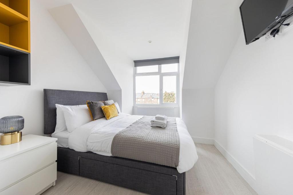 a bedroom with a bed with white walls and a window at Charming Hotel with Kitchen & Laundry near Tufnell Park in London