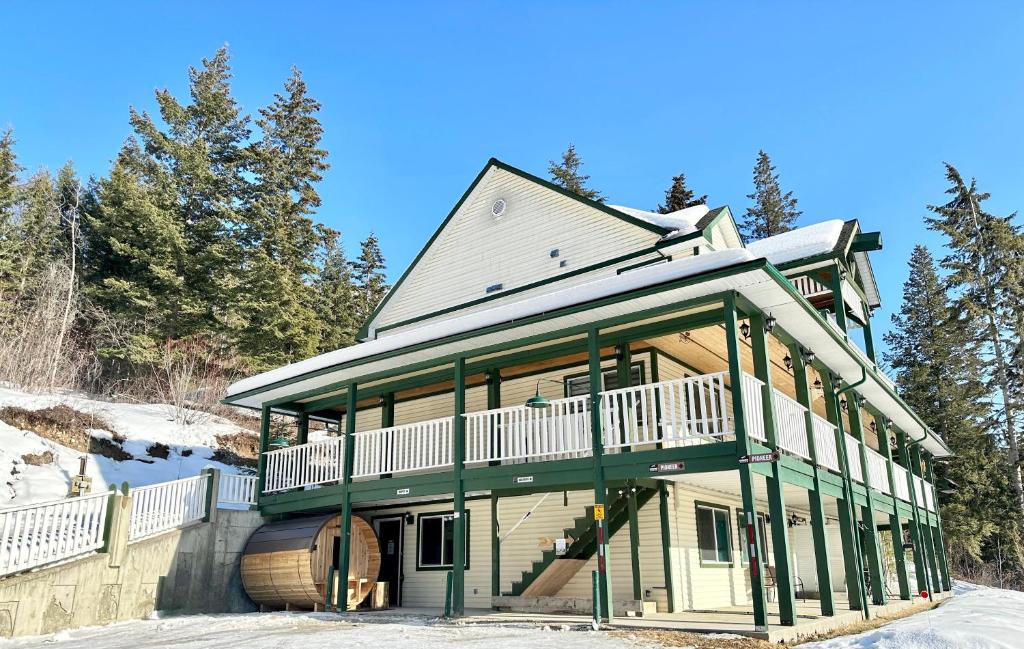 a house with a wrap around porch in the snow at 3mins to Town, AC & Barrel Sauna, Self Check-in, Pet Family Friendly, Full Kitchen, Sleeps 10 in Golden