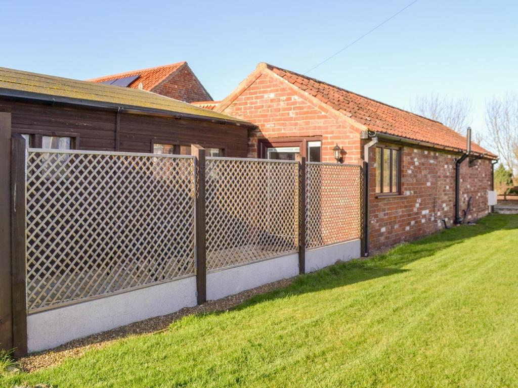 a fence in a yard next to a house at Willow Tree Farm in Sutton on Sea