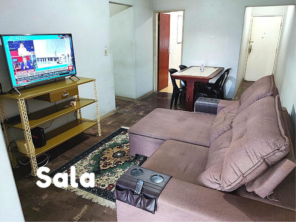 a living room with a couch and a tv at Apartamento em Vitória capital do ES in Vitória