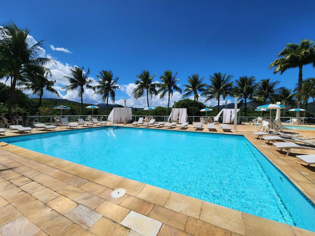 una piscina con tumbonas y palmeras en Apart Hotel Alecrim Praia de Camboinhas com Marina pe na areia en Niterói