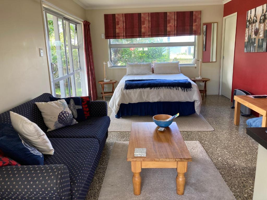 uma sala de estar com uma cama e uma mesa em The Back Garden em Waihi Beach