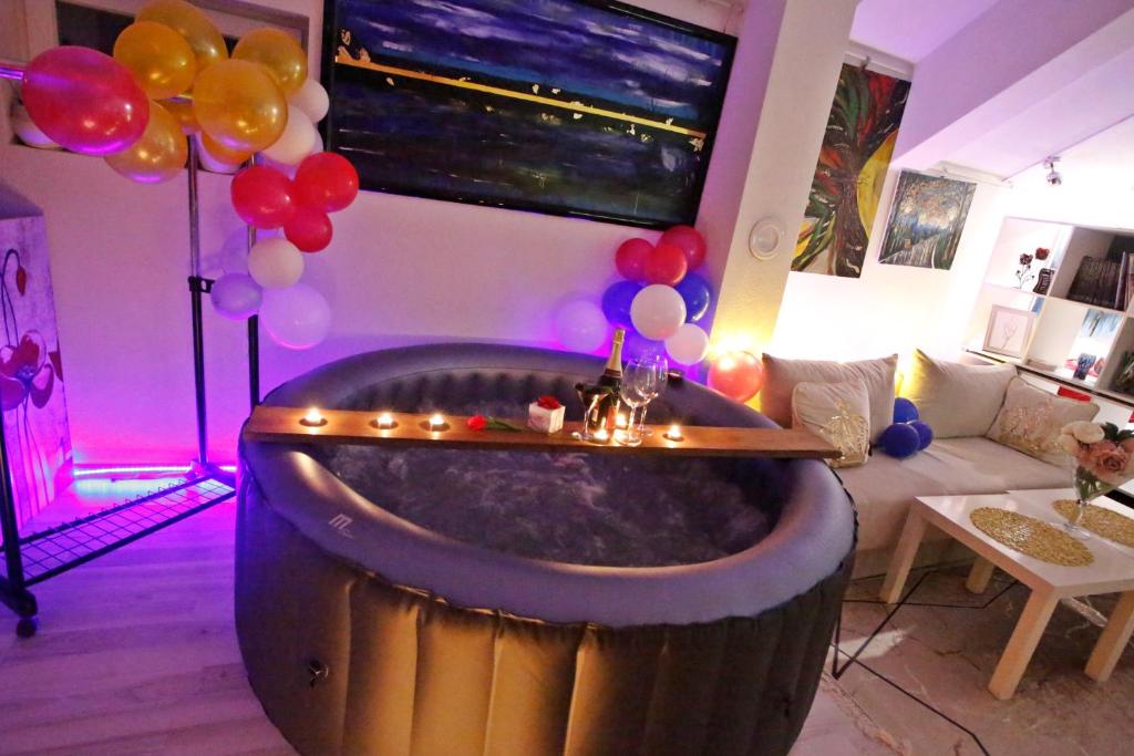 a room with a tub with balloons and a couch at Art apartman in Kakanj