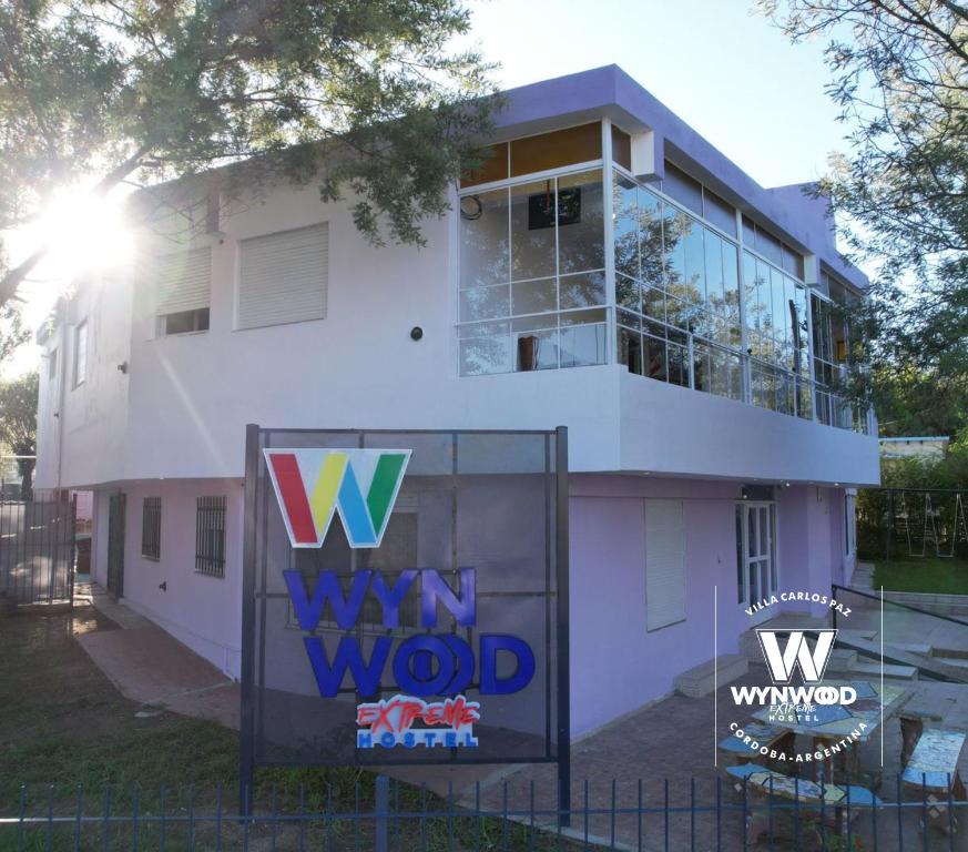 Uma casa branca com um cartaz à frente. em Wynwood Extreme Hostel em Villa Carlos Paz