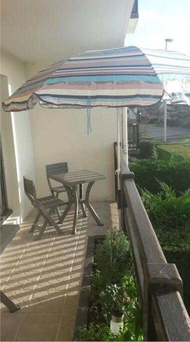 a patio with a table and an umbrella at 2 pièces ensoleillé accès direct plage in Cabourg