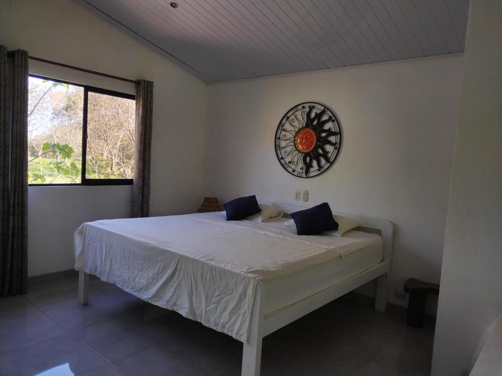 1 dormitorio con 1 cama con reloj en la pared en El Campo, en Savegre