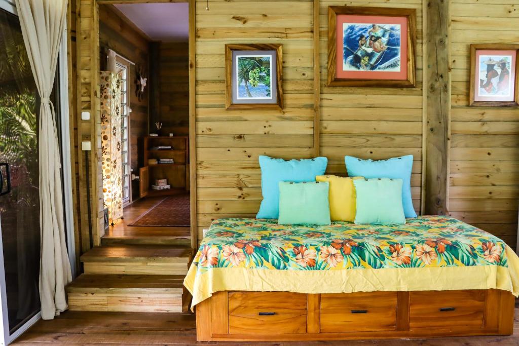 a bedroom with a bed with blue and yellow pillows at Bungalow Bali Hai in Fare