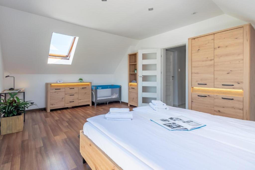a bedroom with a large white bed and wooden cabinets at Familia Apartament na wzgórzu 3 z sauną i salą zabaw dla dzieci in Gdynia