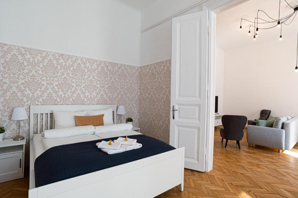 a white bedroom with a bed and a chair at Terrace VuVu - Apartment with balcony in the heart of Budapest in Budapest