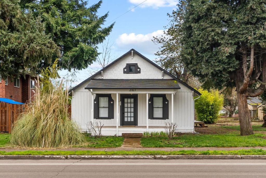 uma pequena casa branca ao lado de uma rua em 2-Bedroom Bungaloo nestled close to Urban Centers em Vancouver