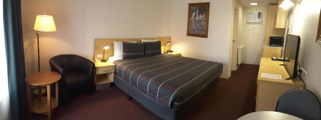 ein kleines Hotelzimmer mit einem Bett und einem Schreibtisch in der Unterkunft Cooma Motor Lodge Motel in Cooma