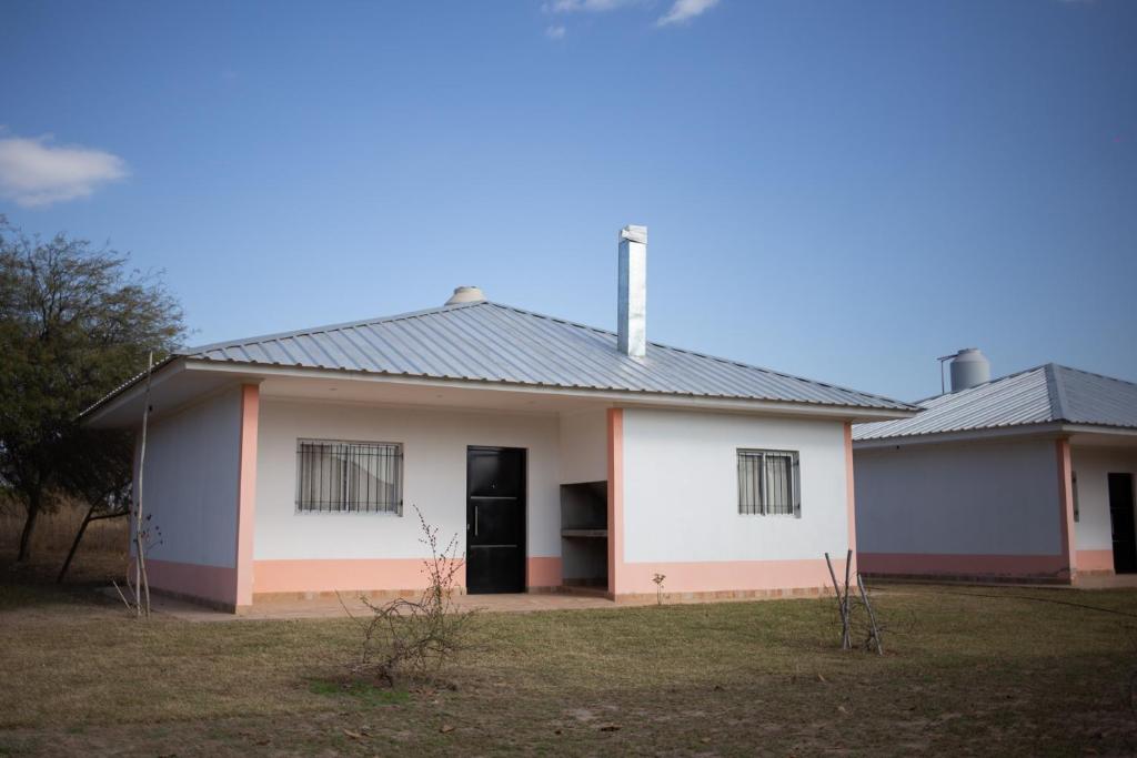 una pequeña casa blanca con techo negro en Las Moras Del Manantial en Termas de Río Hondo