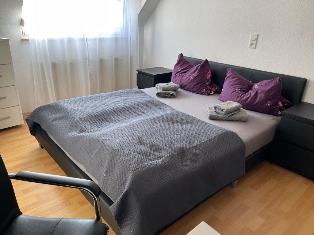 ein Bett mit lila Kissen und einem Stuhl in einem Zimmer in der Unterkunft Ferienwohnung Fürth in Fürth