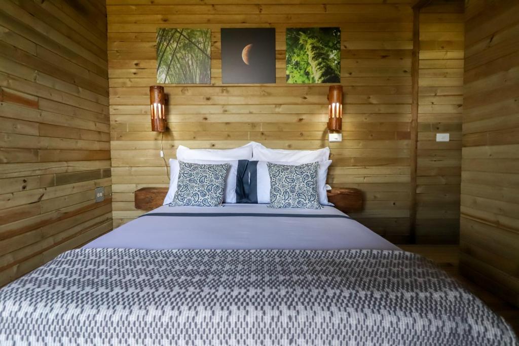 Glamping Encanto de Luna في Fredonia: غرفة نوم بسرير كبير وبجدران خشبية