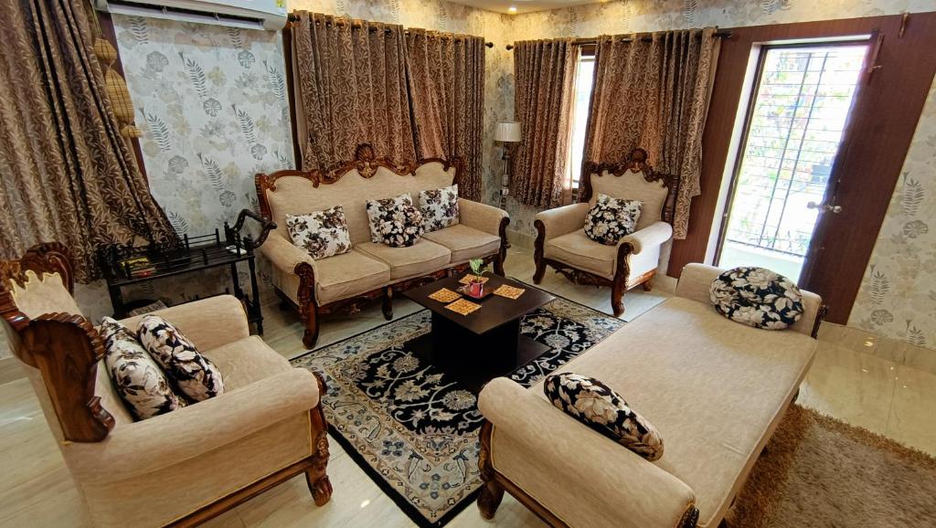 Luxurious studio apartment in Newtown في Thākurdwari: غرفة معيشة بها كنب وكراسي وطاولة