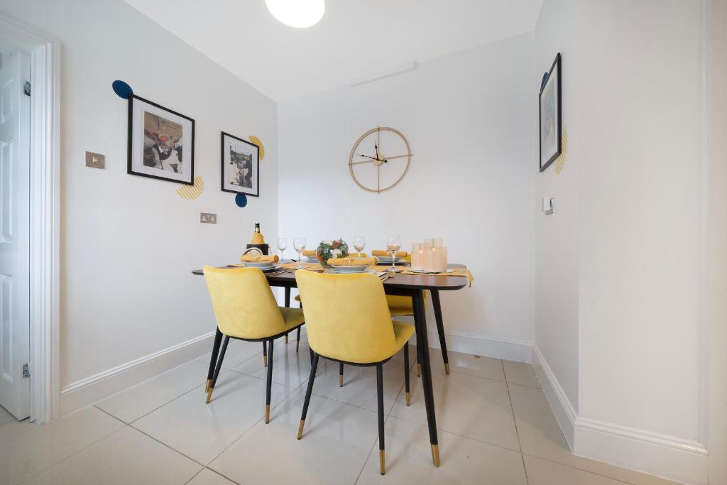 a dining room with a table and yellow chairs at Lovely little house, free on street parking, Smart TV, WiFi in Gloucester