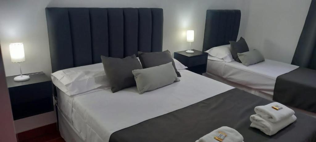 2 camas en una habitación con cortinas azules en Departamentos La Perón en Villa Mercedes