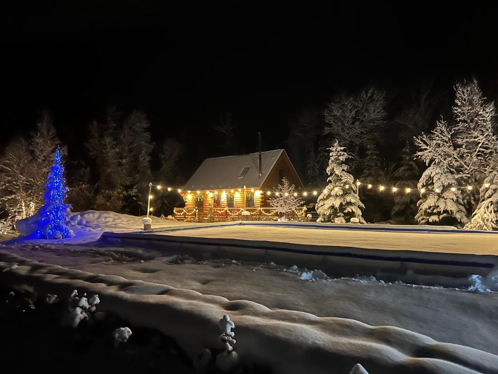 a house decorated with christmas lights in the snow at BC Log cabin with private beach river fire pit AC wifi onsite trails ski slope views in Carroll