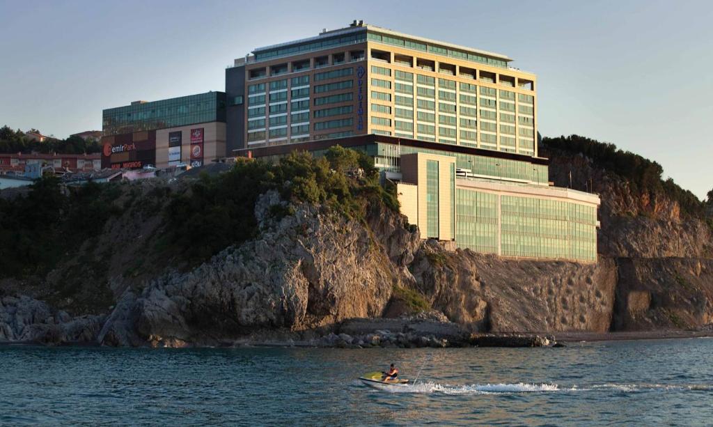 un bâtiment sur une falaise avec un bateau dans l'eau dans l'établissement Dedeman Zonguldak, à Zonguldak