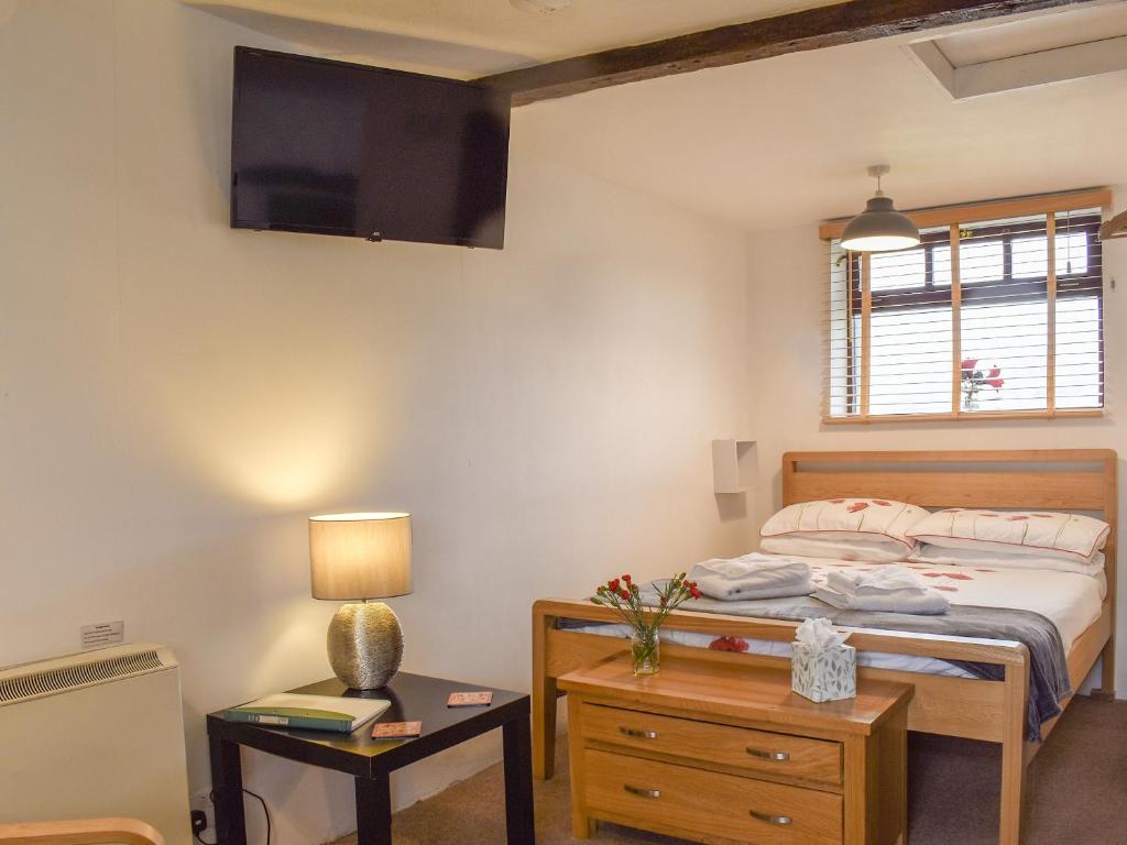 a bedroom with a bed and a tv on the wall at The Snug - Uk42088 in Sedbergh