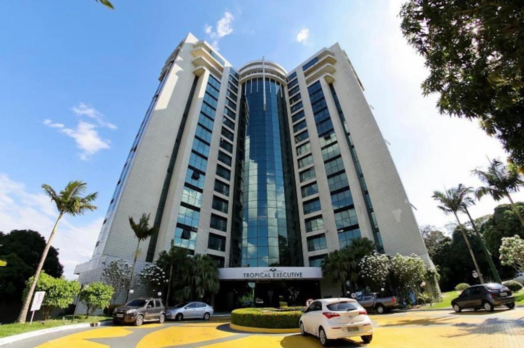 Tropical Executive Hotel N 619 في ماناوس: مبنى كبير به سيارات تقف في موقف للسيارات