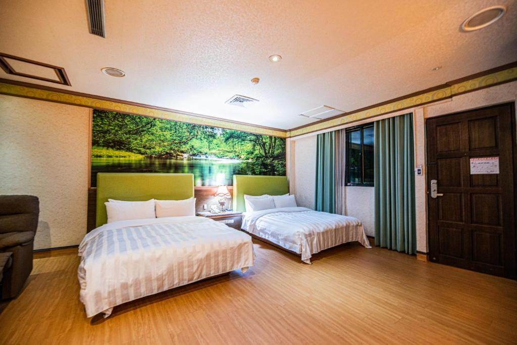 two beds in a room with a painting on the wall at Wenpin Hotel - Pier 2 in Kaohsiung