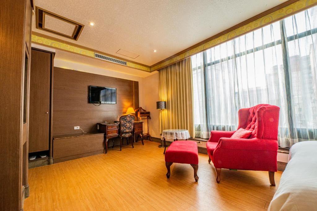 a hotel room with a bed and a red chair at Wenpin Hotel - Pier 2 in Kaohsiung