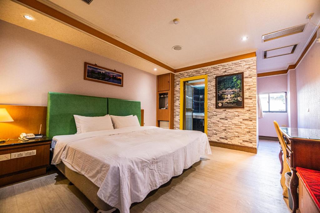 a bedroom with a large bed with a green headboard at Wenpin Hotel - Pier 2 in Kaohsiung