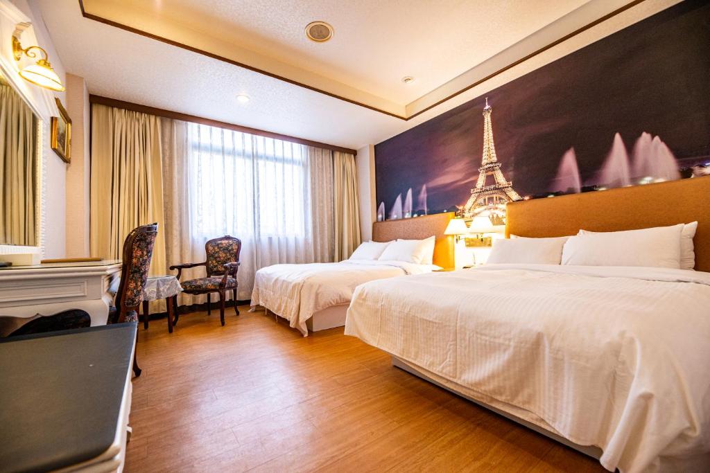 a hotel room with two beds and a eiffel tower mural at Wenpin Hotel - Pier 2 in Kaohsiung