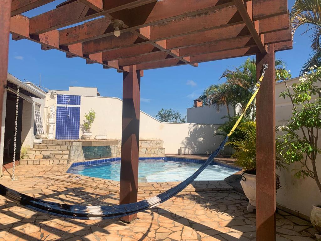 a patio with a hammock next to a swimming pool at Quarto em casa c/piscina in Ouro Fino