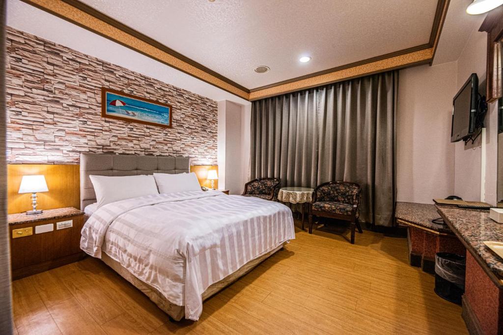 a hotel room with a bed and a table and chairs at Wenpin Hotel - Pier 2 in Kaohsiung