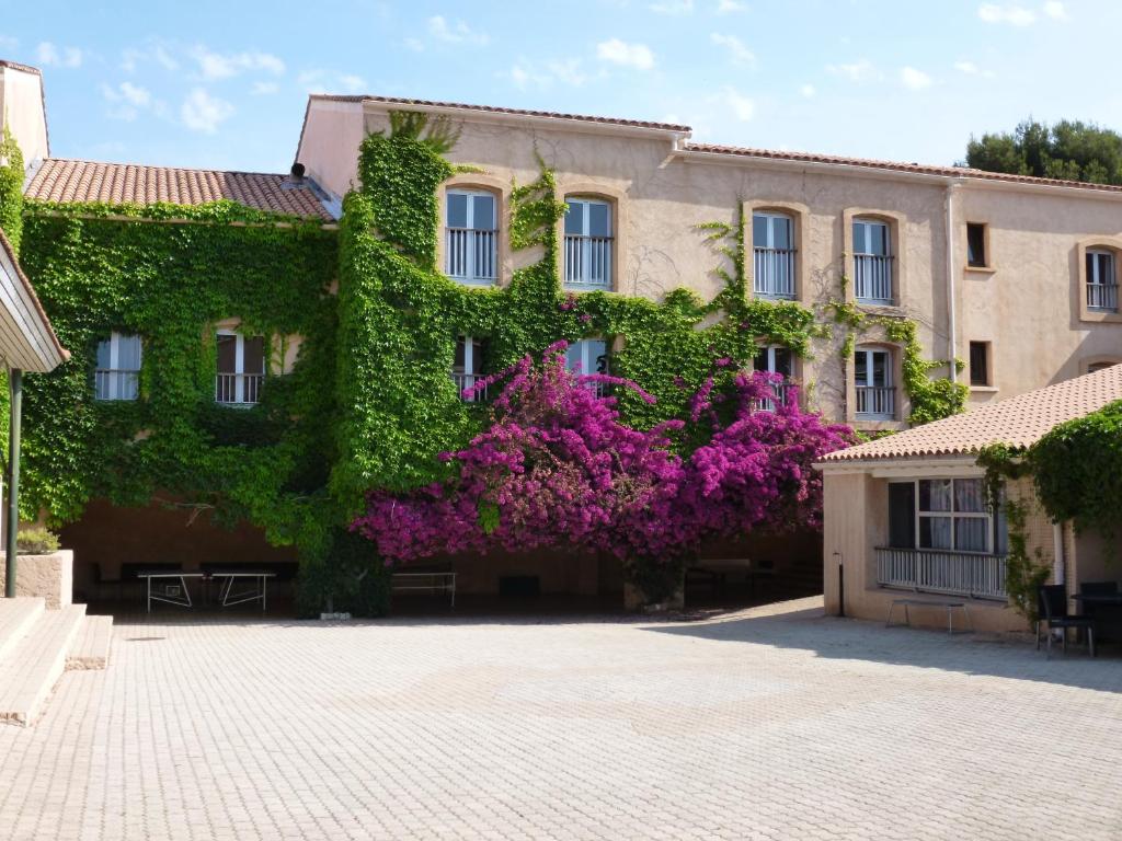 un edificio cubierto de hiedra con flores púrpuras en Les Voiles d'Azur, en La Londe-les-Maures