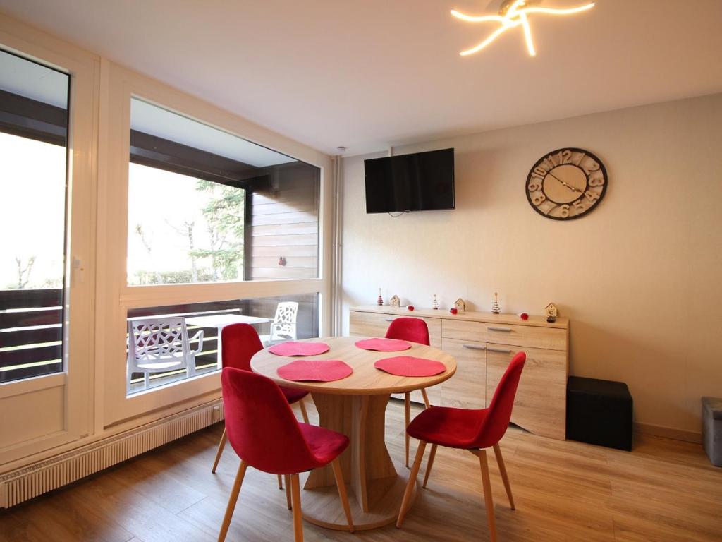 une salle à manger avec une table et des chaises rouges dans l'établissement Charmant T2 avec balcon, parking privatif, idéalement situé au Mont-Dore, proche centre et thermes - FR-1-608-244, à Le Mont-Dore